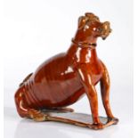 A 19th Century treacle glazed pottery dog flask, probably America Pennsylvania, the seated dog