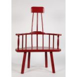 A 20th century Welsh style stick back elbow chair, painted in red, with solid shaped seat, raised on
