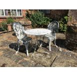 A painted bistro style table and two chairs, with pierced foliate decoration, the table 69cm