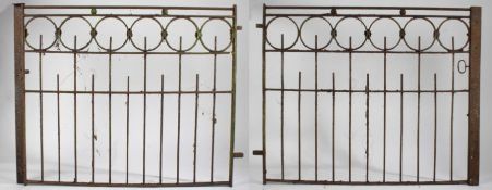 A pair of iron garden gates, each gate with six roundels to the top above railed lower sections,