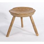 A primitive milking stool, the dished circular seat raised on turned legs, 31cm wide, 28.5cm high