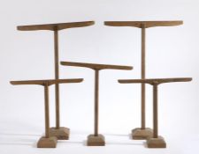 Five wooden stands, of T form, raised on chamfered plinth bases, the largest 41cm wide, 65cm high (