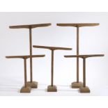 Five wooden stands, of T form, raised on chamfered plinth bases, the largest 41cm wide, 65cm high (