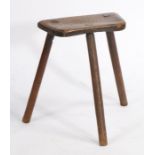An elm milking stool, the seat with canted corners, raised on three out-splayed turned legs, 52cm