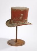 An amusing early 20th Century Tole Top hat trade sign, in red, raised on an associated stand,