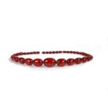 An Art Deco cherry amber necklace, with a row of graduated beads, the largest bead 36mm long, the