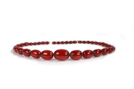 An Art Deco cherry amber necklace, with a row of graduated beads, the largest bead 36mm long, the