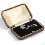 A diamond and emerald set flower brooch, with a central emerald and diamonds to the petal and
