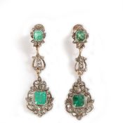 A pair of diamond and emerald set earring drops, set with two emeralds and sprigs containing