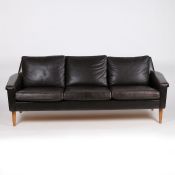 A mid century teak and brown leather three-seater settee, 190cm width x 70cm depth, 69cm height.
