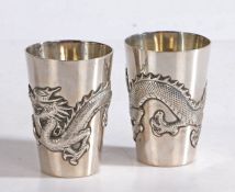 A pair of Chinese silver beakers, maker Wang Hing, the tapering bodies cast with a dragon, 6.5cm