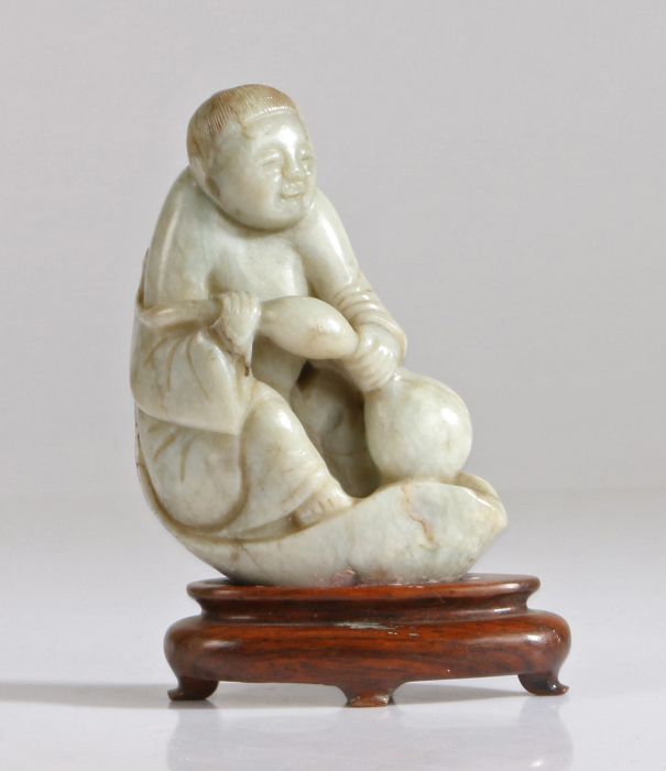 A Chinese jade figure of a boy, Qing Dynasty, 19th Century, carved seat on a lotus leaf petal