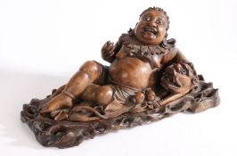 Chinese carved figure of Budai, reclining position with a dog, both set with glass eyes, 33cm