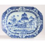A Chinese porcelain export serving platter, in blue and white decorated with buildings and a tree,