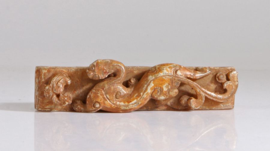 A Chinese jade buckle, Qing Dynasty, 19th Century, carved with a chilong crawling to a small