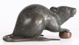 A Japanese Meiji period bronze rat, modelled with front paws on a chestnut, 17cm long, 8.5cm high