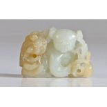 A Chinese white jade group, carved as a boy and Buddhist lion, the jovial figure crouching and