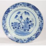 A Chinese export porcelain charger, Qing Dynasty, in blue and white with trees and ritual wares,