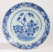 A Chinese export porcelain charger, Qing Dynasty, in blue and white with trees and ritual wares,