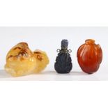 A Chinese carnelian carved peach pendant, a lapiz lazuli snuff bottle and an agate ornament in the