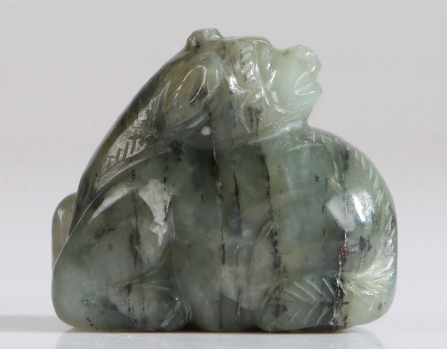 A Chinese jade reclining mythical beast, green and black grained colour, carved into a crouching