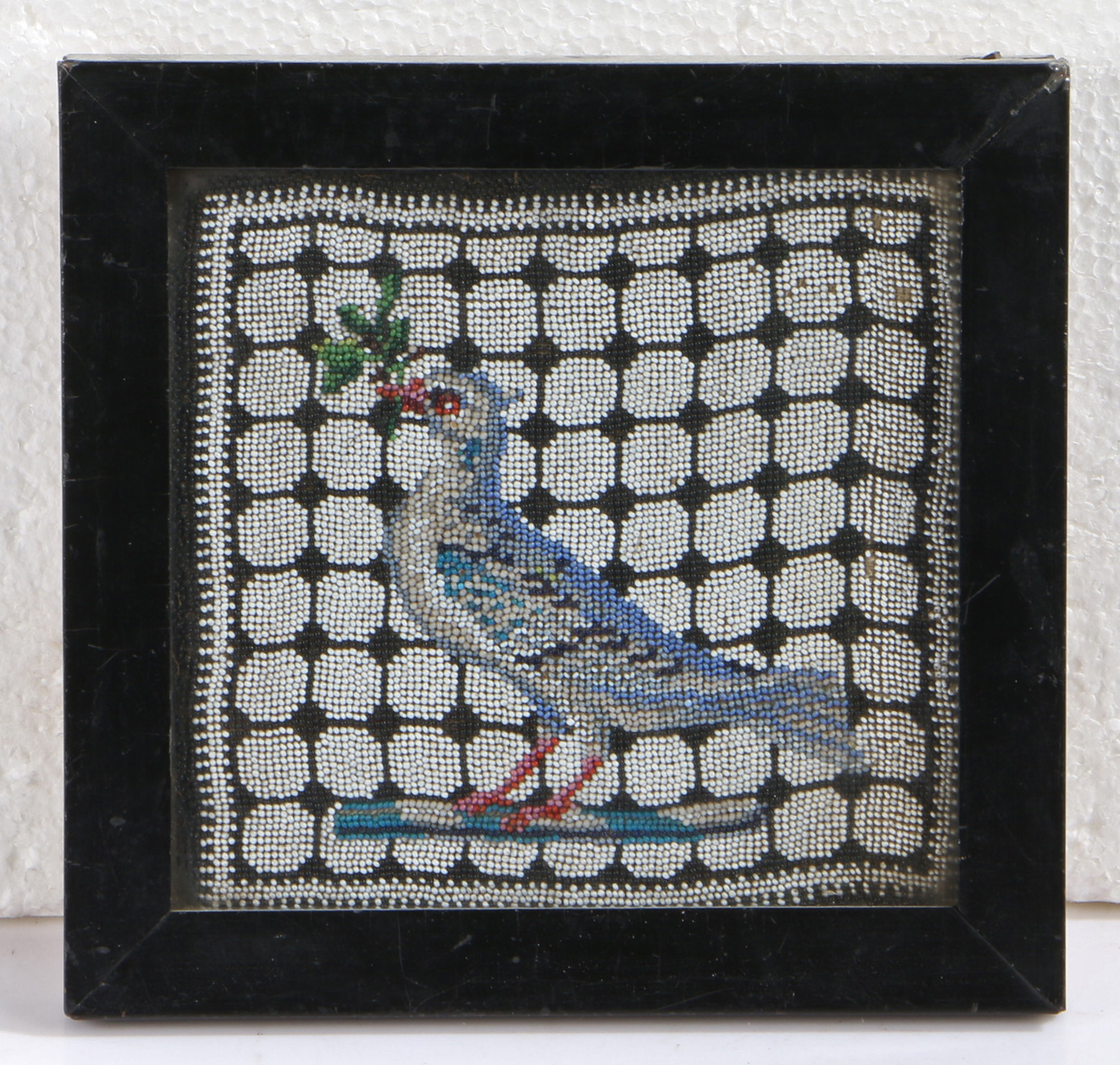 A small 18th century beadwork picture of a dove The dove holding an olive branch within its beak,