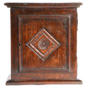 A Charles II oak ‘spice' cupboard, North Country, circa 1670 The panelled door centred with a carved