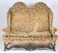 A William & Mary style walnut and upholstered sofa, circa 1900 The double-arched padded back, winged