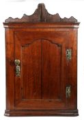 A George II oak corner cupboard, circa 1750 The back boards extending to ornate scroll-profiles