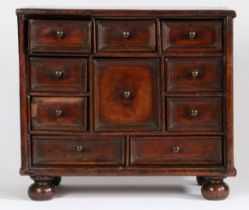 A Charles II oak table cabinet With an arrangement of ten drawers, on turned bun feet, 44.5cm