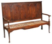 A George II oak settle, circa 1740 The back with five applied arched panels, below a dentil
