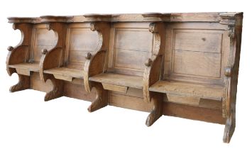 An oak choir stall, in the mid-15th century manner Comprising a run of four seats, each with leafy-