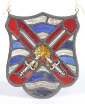 A stained glass panel Of shield shape, designed with crossed-swords centred by a bishop’s mitre,