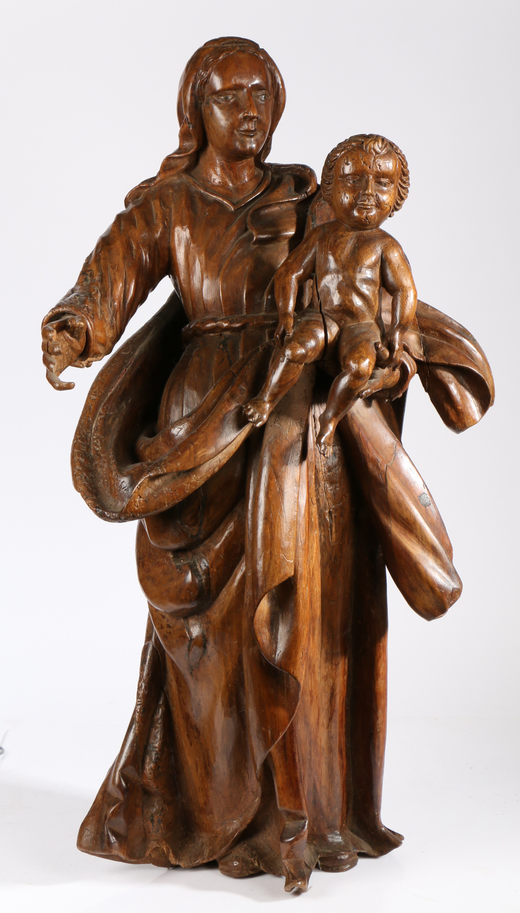 An 18th century walnut figural carving of the Madonna and Child The Virgin wearing flowing robes,