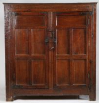 A late 17th Century oak livery cupboard Having a pair of five-panelled cupboard doors, on extended