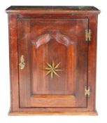 A George II oak and inlaid mural cupboard, circa 1750 Having a fielded and flattened ogee-arched