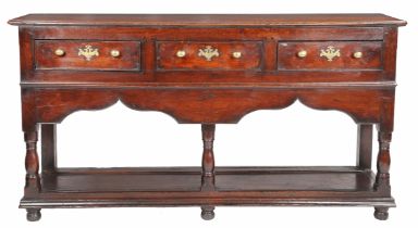 A George II oak open dresser base, Montgomeryshire, circa 1740 Having a boarded top, and three