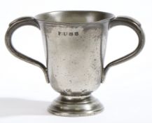A George III pewter twin-handled footed cup, circa 1800 Having a tulip-shaped pint capacity drum,