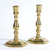 A pair of George I seamed brass candlesticks, circa 1720 Each with a thistle-shaped sconce, baluster