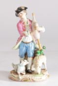 A Meissen porcelain figure of a young man playing the pipes with a dog and a lamb at his feet,