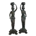 A pair of Italian bronzed Blackamoor candlestick figures, formed as a man and a woman holding a