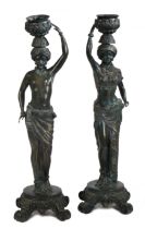 A pair of Italian bronzed Blackamoor candlestick figures, formed as a man and a woman holding a