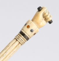 A George III whalebone and inlaid walking stick, the handle in the form of a clenched fist holding a