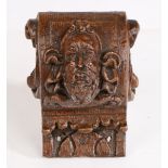 A 17th Century continental carved oak corbel, carved with a bearded man and swags to the C scroll