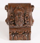 A 17th Century continental carved oak corbel, carved with a bearded man and swags to the C scroll