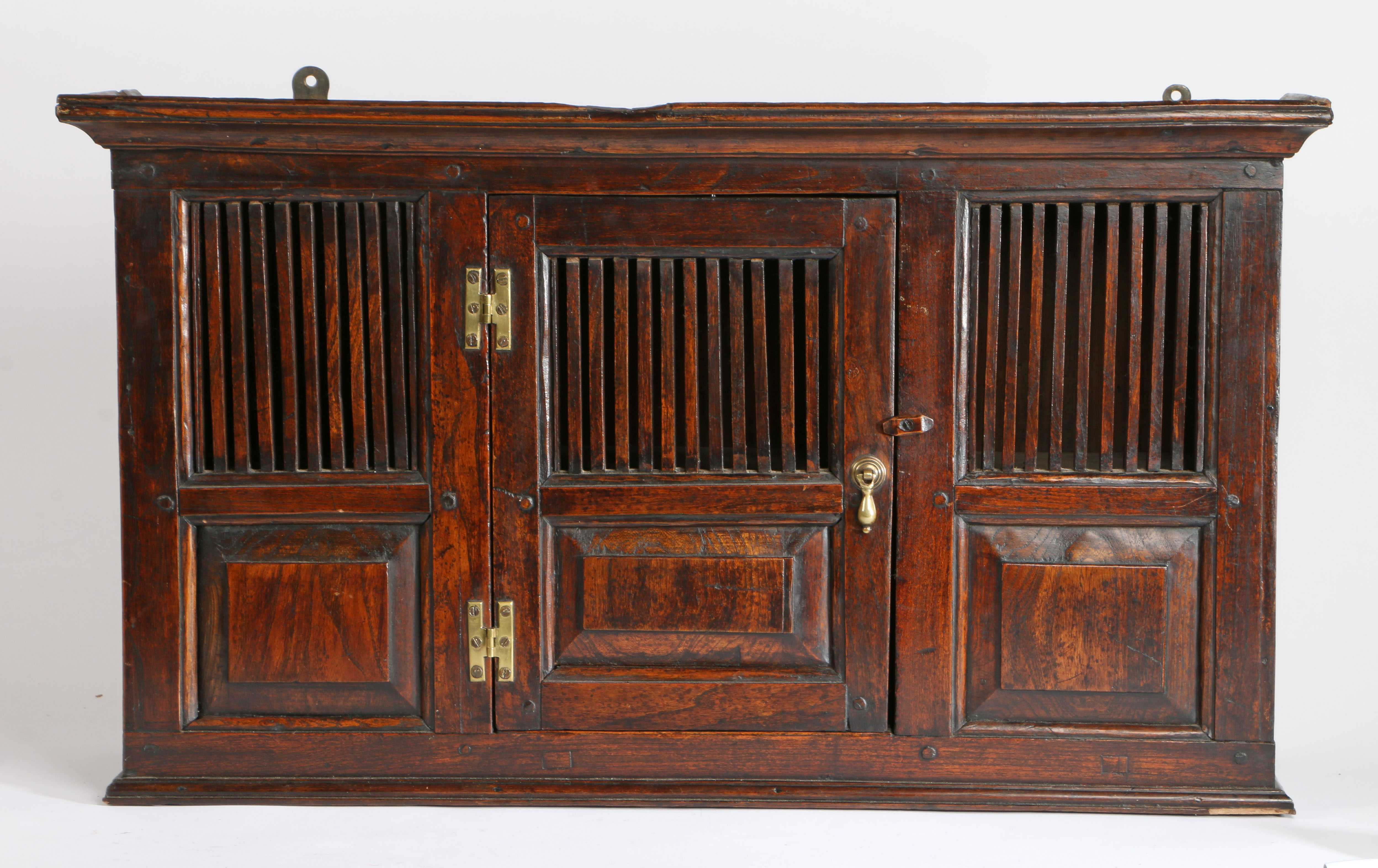 An elm spindle mural cupboard in the 18th century manner, the concave cornice above a spindle and