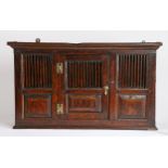 An elm spindle mural cupboard in the 18th century manner, the concave cornice above a spindle and