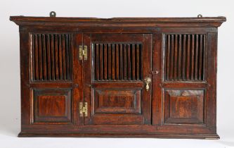 An elm spindle mural cupboard in the 18th century manner, the concave cornice above a spindle and