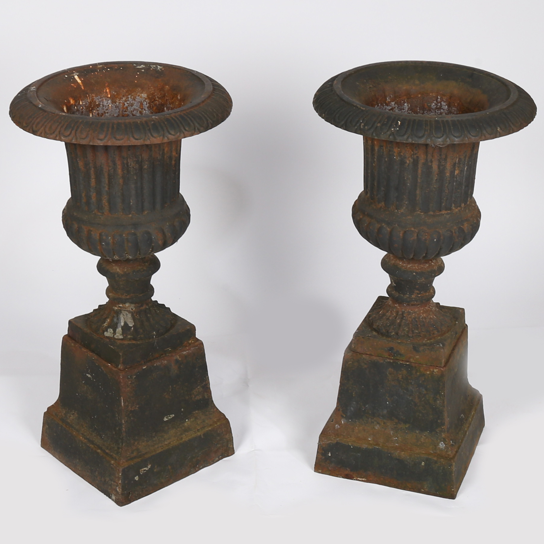 A pair of 19th century cast iron garden urns of campana form, having a frilled flange above a