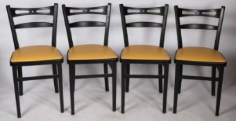 A set of four painted and vinyl upholstered dining chairs in black and tan, stamped to the underside